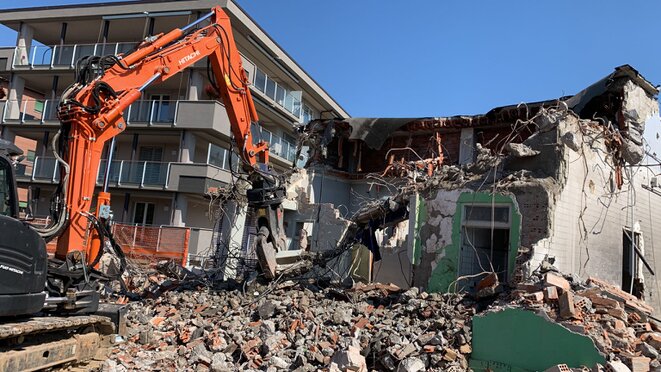 Demolizione parziale di un edificio industriale con escavatore